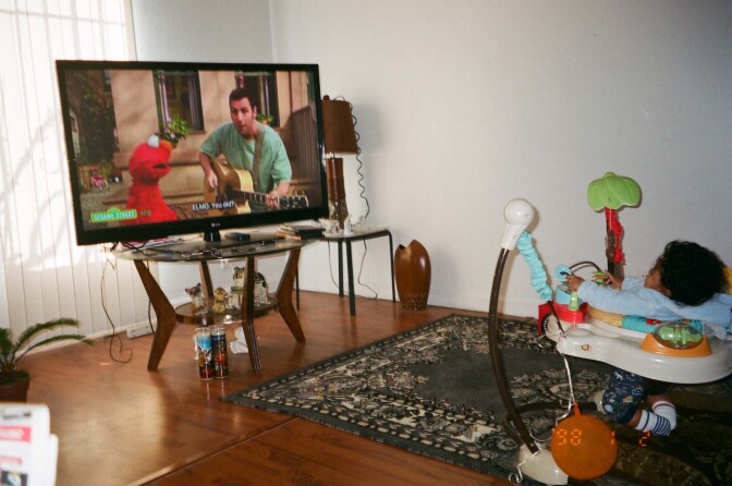 Hunter sits in a baby walker watching Sesame Street.