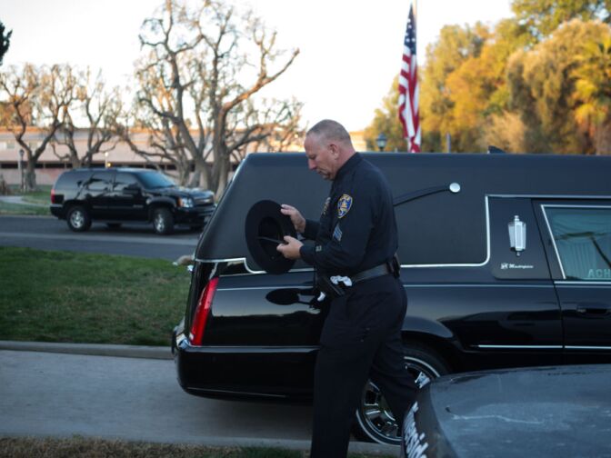 An officer adjusts his hat near the hearse that will drive Michael Crain's body to Grove Community Church, where funeral services for Crain will be held.