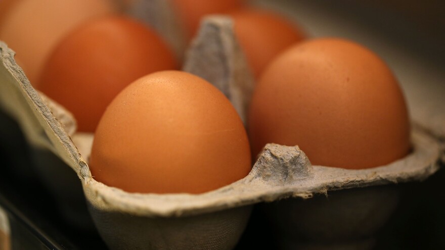 A partial view of container of a dozen brown eggs.