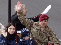 Army Sgt. First Class Eric Pazz rides with his wife Miriam and son Eric Jr., after they were reunited in the 124th Rose Parade in Pasadena, Calif., Tuesday, Jan. 1, 2013. Miriam Pazz had been told she had won a contest to attend the parade and did not know her husband, who is deployed in Afghanistan, would be riding on the Natural Balance Pet Foods float. Pazz is a highly-decorated soldier who has also served in Iraq. (AP Photo/Patrick T. Fallon)