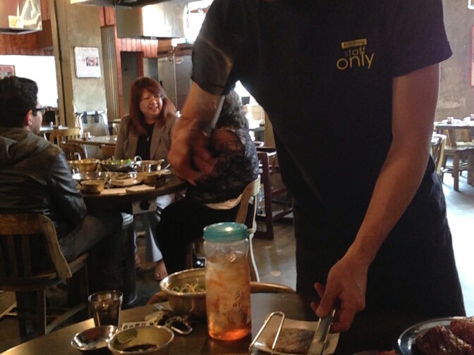 A Baekjeong server barbecues meat. 