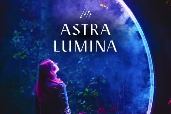 A poster for Astra Lumina, a late night walking experience. The dark blue and purple poster features a woman starting up at some stars while she is illuminated.