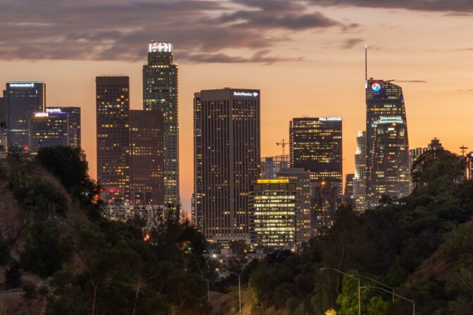Tall skyscrapers appear against a sky at dusk.