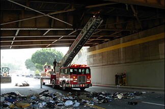 LAPD officers climbed the city fire department's ladder truck to remove the accumulations of a homeless person who lived on top of a ventilator that spans Figueroa Street under the First Street bridge. Some of that trash fills the street below.