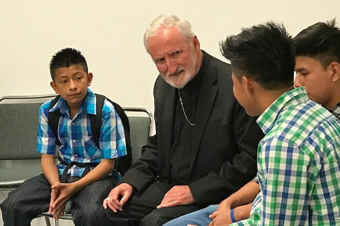 Auxiliary Bishop David O’Connell sits with three young children.jpg