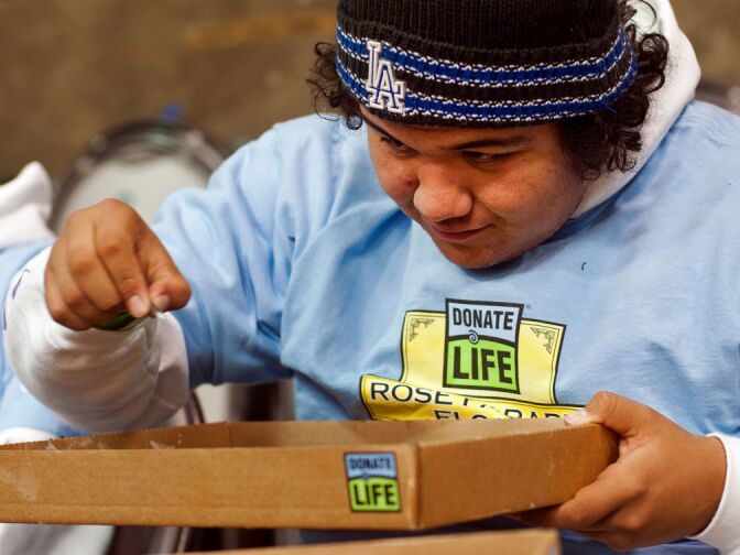 Arturo Bravo Chavez picks apart onion seeds, which will be used to add color to the Donate Life float.