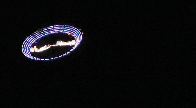 US plastic artist Peter Coffin's "Flying Saucer" --a 7-meter, LED-studded, SMS-controlled flying saucer and lifted by a helicopter-- overflies Ipanema beach, on May 23, 2009, in Rio de Janeiro, Brazil.  AFP PHOTO/Antonio Scorza (Photo credit should read ANTONIO SCORZA/AFP via Getty Images)