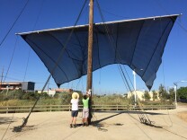 Artists Joshua Callaghan, left, and Daveed Kapoor, right, raise the sails on their sculpture, Mast, on July 15, 2016. The sculpture is part of LA's first public art biennial, CURRENT:LA, and is located in South LA Wetlands Park.