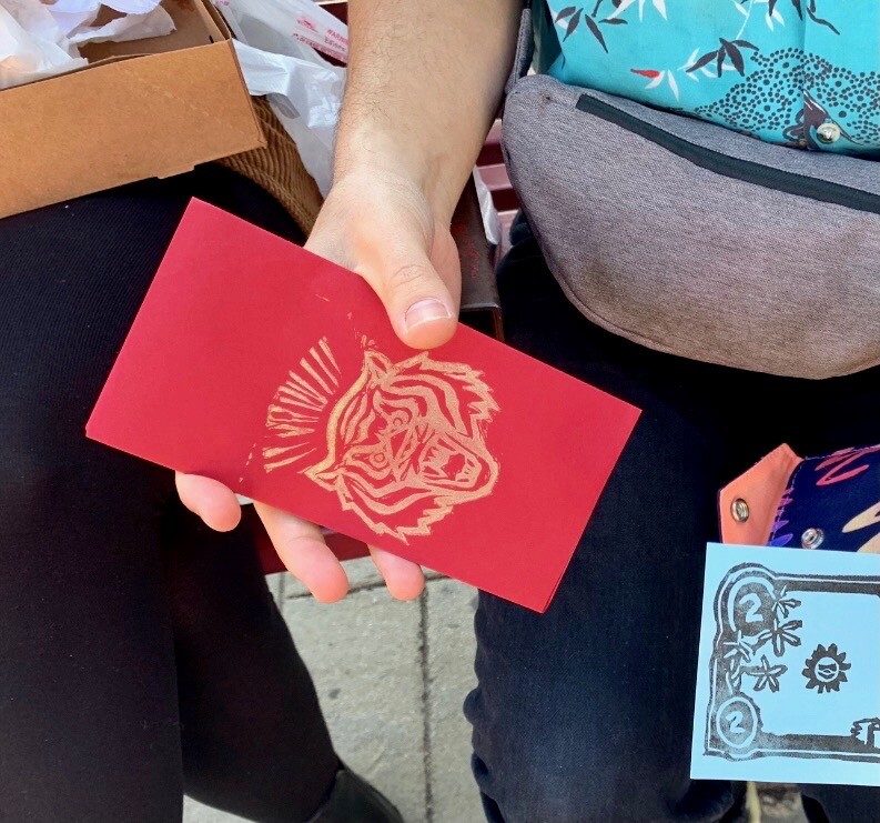 A hand holds a red envelope stamped with a gold tiger