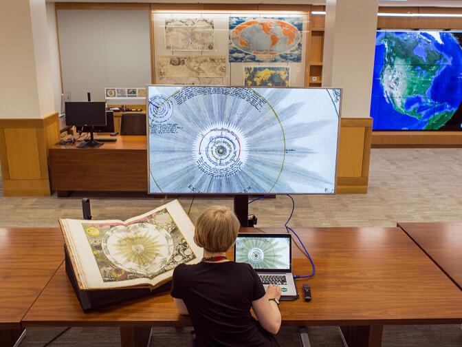 Deardra Fuzzell, a cartographic technology specialist at Stanford inspects a 1742 celestial atlas in both paper and digital form at the new David Rumsey Map Center. 