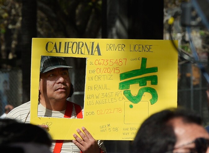 LOS ANGELES, CA - OCTOBER 03:  Raul Ortega holds a sign as he celebrates after California Governor Jerry Brown signed bill AB60 on the steps of Los Angeles City Hall  October 3, 2013 in Los Angeles, California. California Assembly Bill 60 also known as the Safe and Responsible Driver Act allows illegal immigrants to receive a permit to legally drive in California.  (Photo by Kevork Djansezian/Getty Images)