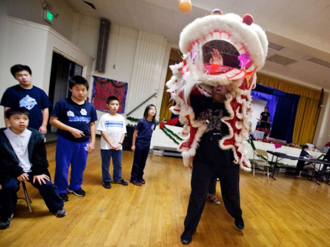 Alex Dea, 16, throws an orange in the air, part of the traditional performance during Chinese New Year. Businesses leave a red envelope filled with money above a front door or table, and lion dance groups perform for the reward.