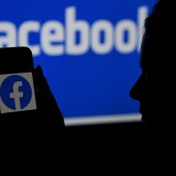 In this photo illustration, a smart phone screen displays the logo of Facebook on a Facebook website background, on April 7, 2021, in Arlington, Virginia - Facebook usage has held steady in the United States despite a string of controversies about the leading social network, even as younger users tap into rival platforms such as TikTok, a survey showed Wednesday. (Photo by OLIVIER DOULIERY / AFP) (Photo by OLIVIER DOULIERY/AFP via Getty Images)