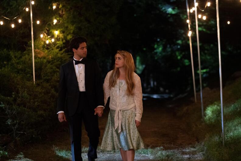 Two people, a man and women, hold hands while staring at one another.