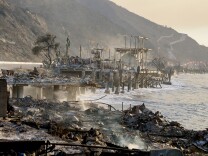Smoldering ruins on pillars that are set into the ocean.