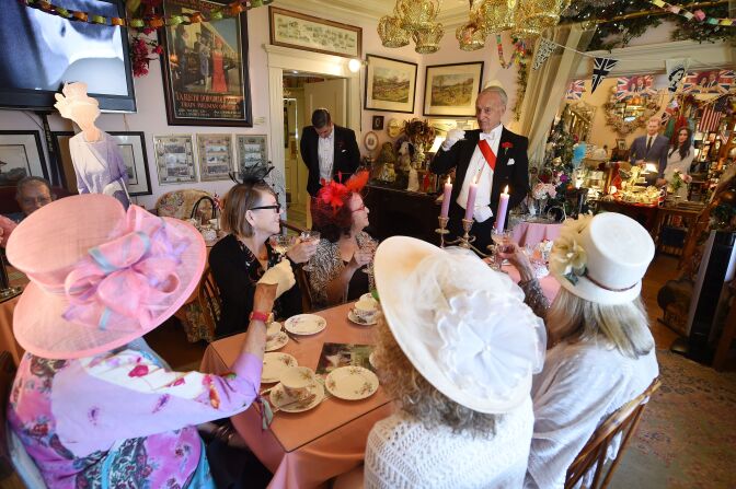 Edmund Fry (R) leads guests in a toast to Prince Harry and Meghan Markle during an afternoon tea service at The Rose Tree Cottage in Pasadena, north of Los Angeles, California, May 15, 2018, where Meghan Markle has been a guest, Fry offering her tips on how to correctly partake in afternoon tea. - The Rose Tree Cottage will celebrate the wedding of Prince Harry and Meghan Markle with a high tea on Saturday, May 19, 2018 with replays of the royal wedding on the television. Guests are suggested to dress up in the spirit of the wedding, in "bridesmaid dresses, veils or whatever they have in their cupboard." (Photo by Robyn Beck / AFP)        (Photo credit should read ROBYN BECK/AFP/Getty Images)