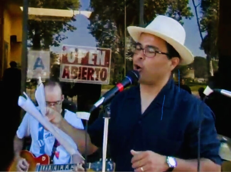 Person with a hat reading a poem in front of a microphone.