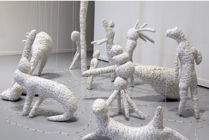 A series of white statues shaped as abstract animals with Persian/farsi language written on them.