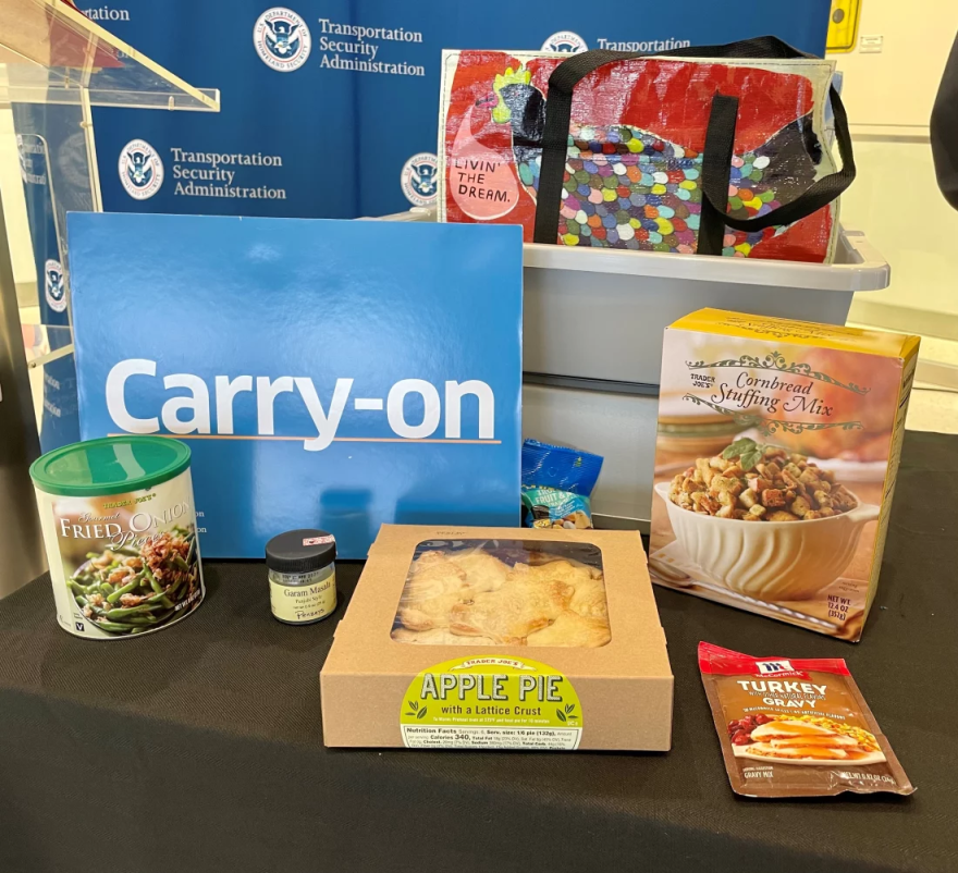 packaged thanksgiving food on a table next to TSA signs and a giant one that says "Carry-on"