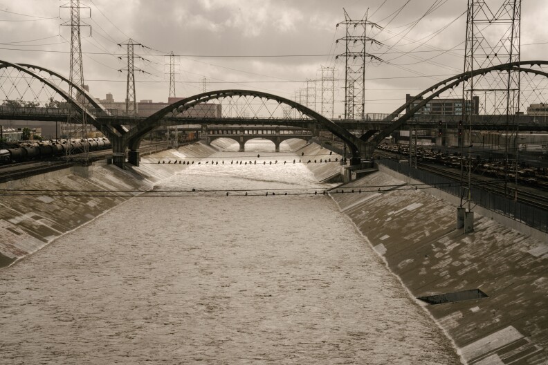 A concrete riverbed is filled with surging water after a rain storm.
