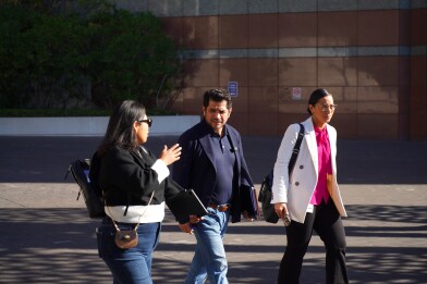A man and two women walk out of a federal building.