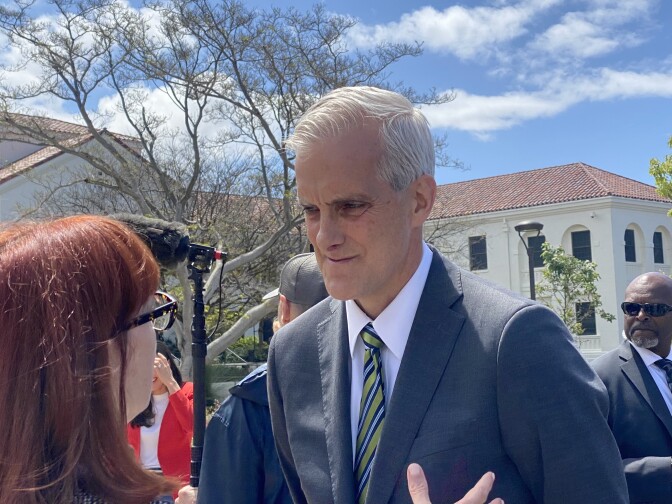 A man looks towards a woman who's speaking to him outside a building at the West Los Angeles Veterans Affairs campus.