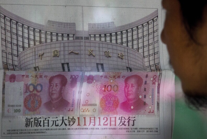 A man reads a newspaper reporting that China's central bank or People's Bank of China announced the 2015 edition of the 100 renminbi notes will be issued starting from November 12, at a stand in Beijing Tuesday, Aug. 11, 2015. China devalued its tightly controlled currency on Tuesday following a slump in trade, triggering the yuan's biggest one-day decline in a decade. (AP Photo/Andy Wong)
