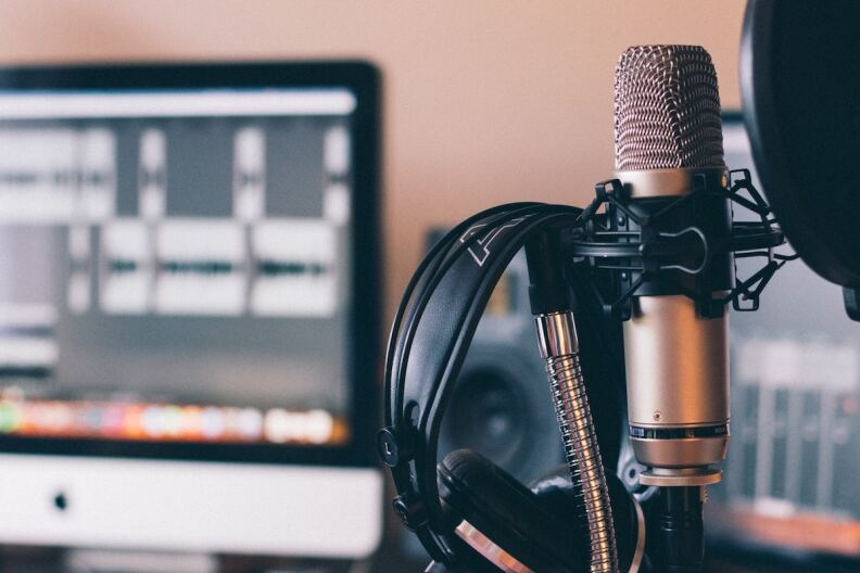 A mic, headphones and a computer are set up for podcasting.