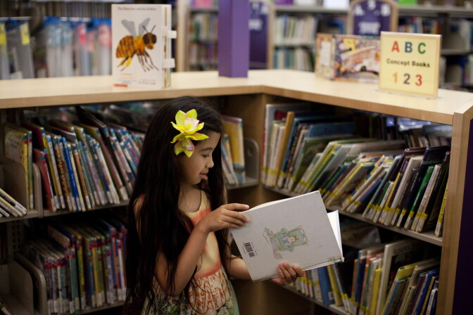 Arianna Anderson, 9, looks at a book at the Torrance Public Library. Her parents, Hilda and Brent, worry she is losing her love of reading, because the school is not providing services tailored to her needs.
