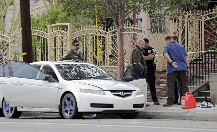 Investigators view items removed from a car, left, after a heavily armed man was arrested in Santa Monica, Calif., early Sunday, June 12, 2016. The man reportedly told police he was in the area for West Hollywood's huge gay pride parade. Authorities did not know of any connection between the gay nightclub shooting in Orlando, Fla., early Sunday and the Santa Monica arrest.