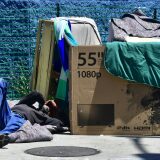 A homeless man sleeps beside his makeshift temporary shelter on a street in downtown Los Angeles, California on June 25, 2018, as a United Nations report on poverty and inequality says 185 million Americans are living in extreme poverty.