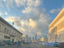 Makeshift tents line with both sides of a city street with tall skyscrapers visible in the background.