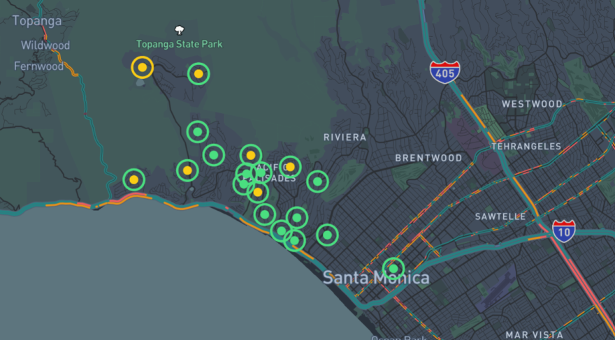 A map of Santa Monica, Pacific Palisades, Brentwood, Topanga and other neighborhoods. The map is green and grey, with yellow, red and green lines marking the 10 and 405 freeways. There are small circles with dots in them to mark the location of air quality sensors. Most of the circles and dots are green, but some are yellow.