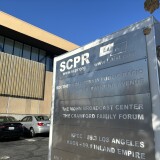 A metal sign outside a large beige building lists SCPR and LAist side-by-side.