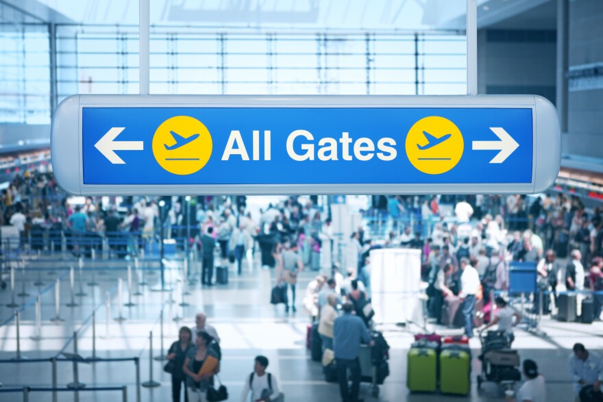 A sign reads: All Gates above a large lobby area at an airport