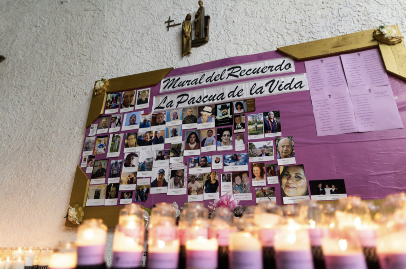 Photos of people who have died during the pandemic on a board mounted on the wall of a church.