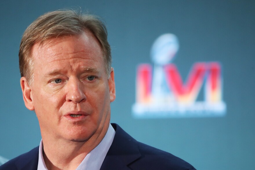 A close up of Roger Goodell in front of a faded Super Bowl logo.