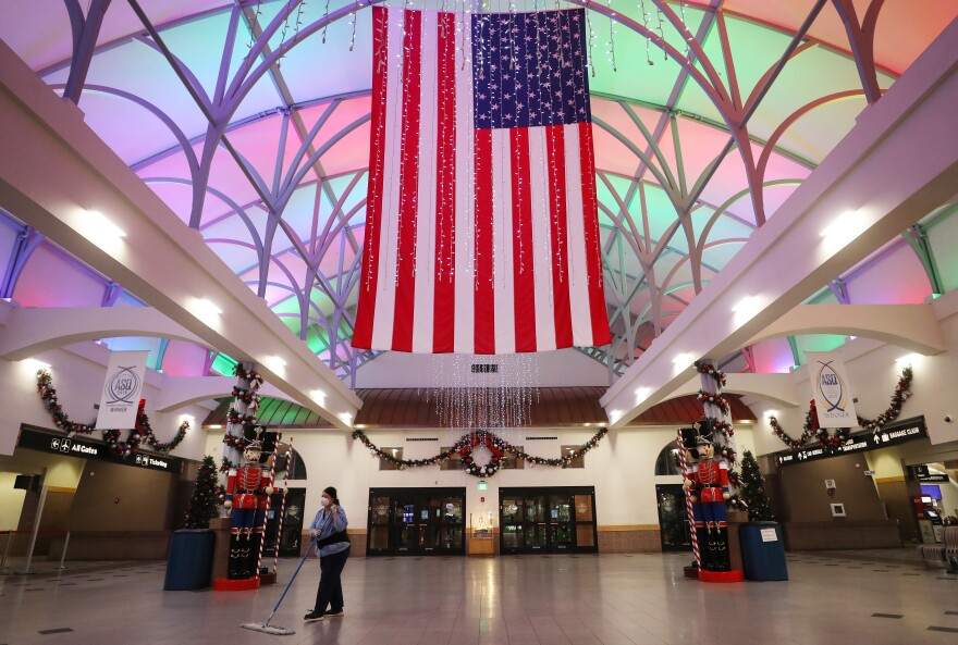 EL PASO, TEXAS - NOVEMBER 12: A worker cleans near an American flag and Christmas decorations in the mostly empty El Paso International Airport amid a surge of COVID-19 cases on November 12, 2020 in El Paso, Texas. Texas eclipsed one million COVID-19 cases November 11th with El Paso holding the most cases statewide. More than 1,000 are hospitalized with COVID-19 in El Paso with around 300 of those patients in the ICU amid a court battle over a shutdown of nonessential businesses. (Photo by Mario Tama/Getty Images)