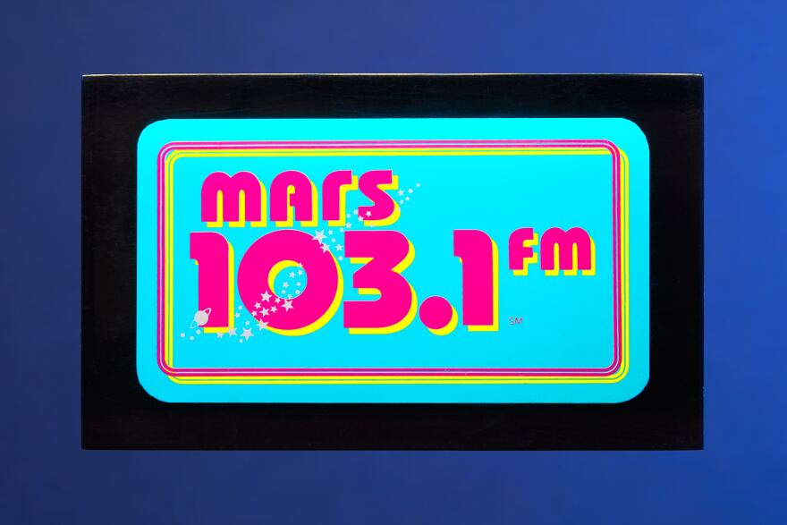 MARS FM Logo, which has a light blue background and pink characters highlighted with yellow.