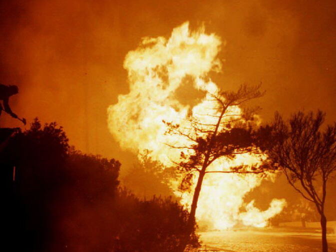 A fireman (L) atop a house tries to fight an out of control gas main blaze following a 6.6 earthquake in Southern California Jan. 17, 1994. The earthquake was centered in the San Fernando Valley.