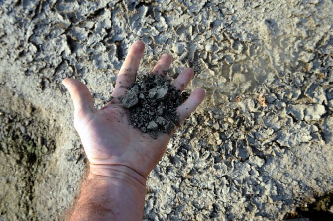 A man holds dirt in the bed of the Garonne river taken on September 11, 2012 in Toulouse, south western France, where the ground-water level is extremely low due to the lack of rain in the last months.