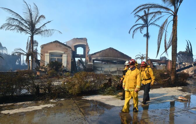 Firemen survey the damage to homes in the Anaheim Hills neighborhood on October 9, 2017, after the Canyon Fire 2 spread quickly through the area.