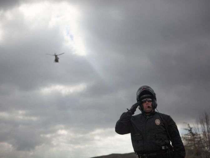 A San Bernardino police officer stands at attention at Glen Ellen Park as the funeral procession for Det. Jeremiah MacKay passes by.