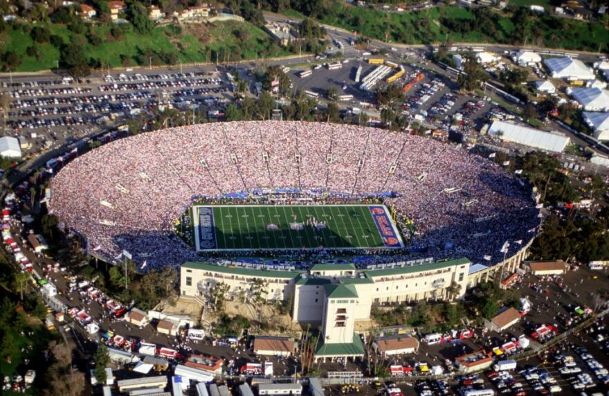 An aerial, daytime shot of the Rose Bowl during a packed Super Bowl. Homes and trees are visible around the arena.