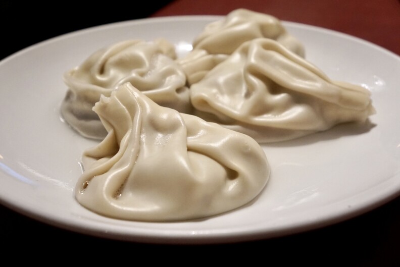 Four dumplings rest on a white plate.
