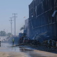 Crews clean up debris from a burned building.