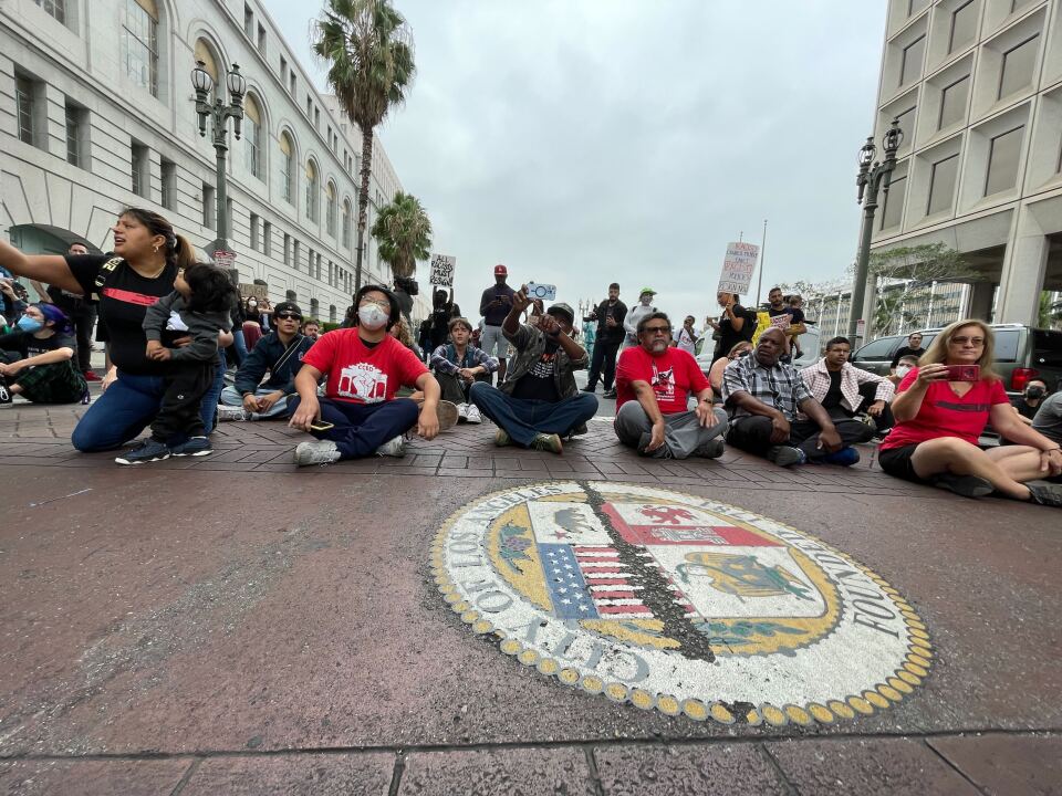 People sir cross-legged in the street holding protest signs