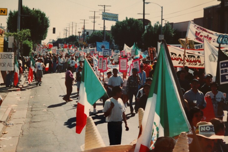 Marchers crowd a street carring flags and banners.