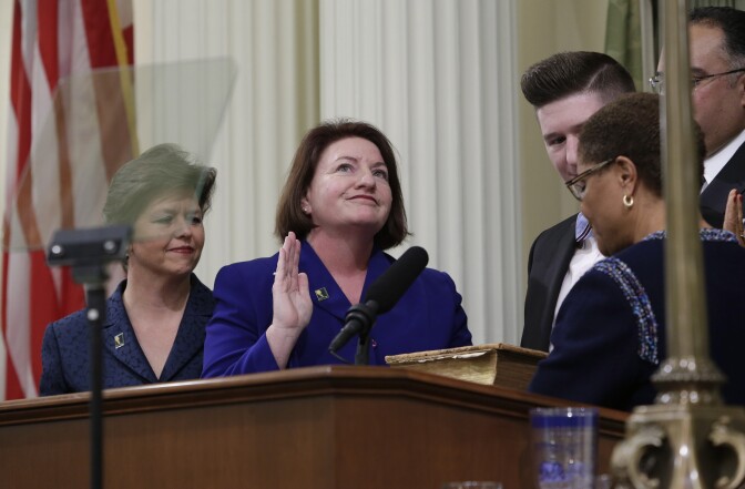 Toni Atkins, D-San Diego, second from left, smiles as she looks up to friend seated in the Assembly Gallery as she is sworn in as 69th Assembly Speaker by former Assembly Speaker, Rep. Karen Bass, D-Calif., right, at the Capitol in Sacramento, Calif., Monday, May 12, 2014.  Atkins replaces Assembly Speaker John Perez, D-Los Angeles, who is termed out.  Atkins was accompanied by her spouse, Jennifer LeSar, left, and her nephew, Thomas Phillips, second from right.(AP Photo)