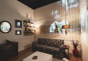 A living room setting with a couch, table, and older television. There is a bookshelf, a mirror, and paintings on the wall, as well as photos, including one of Black rights activist Martin Luther King Jr. A family photo in black and white is projected on the wall, showing a small Black child and another Black person.